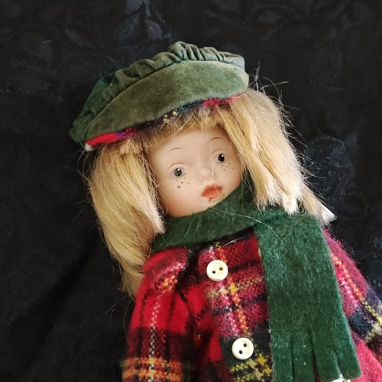 Muñeca de porcelana con bufanda verde